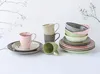 A collection of ceramic tableware, including mugs and plates, arranged on a white surface with decorative branches in the background. Náhľad obrázku produktu