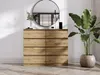 A dresser with eight drawers is shown in a well-lit room with a large round mirror above it and a potted plant to the right. Náhľad obrázku produktu