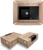 A top-down view of a black kitchen sink inside an open cardboard box, and two closed cardboard boxes below. Produktbild-Vorschau