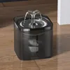 A pet water fountain is shown on a wooden floor, with a white wall in the background. Produktbild-Vorschau