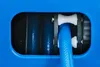 A close-up view of a blue hose reel mechanism with a blue hose threaded through white rollers. Produktbild-Vorschau