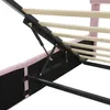 Close-up view of the underside of a pink upholstered bed frame, showing the hydraulic lift mechanism and wooden slats. Podgląd zdjęcia produktu