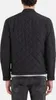 A person wearing a black quilted jacket and jeans, viewed from the back. Produktbild-Vorschau