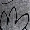 A close-up of a textured gray fabric with black abstract lines. Produktbild-Vorschau