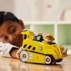 A young boy is playing with a yellow toy vehicle on a wooden table. Náhled obrázku produktu