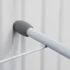 A close-up shot of a white metal radiator drying rack with a gray rubber tip resting against a white radiator. Produktbild-Vorschau