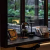 A desk setup with headphones, a CD player, and books next to a window with a view of greenery. Produktbild-Vorschau