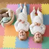 Two babies lying on a colorful play mat with toys in a basket. Produktbild-Vorschau