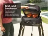 A person is using a grill outdoors with two chickens cooking on it. Voir les images du produit