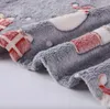 A close-up view of a soft, gray blanket with a festive Christmas pattern of red and white gift boxes and possibly Santa Claus figures. Náhled obrázku produktu