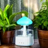 A mushroom-shaped humidifier with a blue light is placed between two potted plants, with raindrops visible on a window in the background. Náhled obrázku produktu