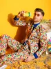 A man in a colorful confetti suit sits on the floor with confetti scattered around him. Anteprima dell’immagine prodotto