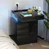 A bedside table with a drawer pulled out, showing a phone charging and a decorative item. Produktbild-Vorschau