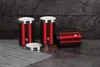 Three red canisters with silver lids are arranged on a dark countertop against a dark gray textured wall. Náhled obrázku produktu