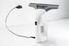 A white electric window cleaner is shown plugged into a wall socket with a black cord. Voir les images du produit