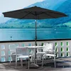 An outdoor patio scene with a table and chairs under a large umbrella, overlooking a lake and mountains. Voir les images du produit