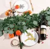 A festive table setting with a garland, plates, cutlery, and a bottle of wine. Anteprima dell’immagine prodotto