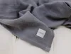 A close-up of a gray muslin blanket with a white label. Produktbild-Vorschau