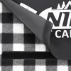 Close-up of a picnic blanket showing its checkered pattern and a folded section revealing the underside and velcro closure. Produktbild-Vorschau