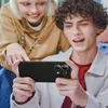 Two young people are looking at a smartphone held by one of them. Produktbild-Vorschau