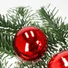 A close-up view of red Christmas ornaments on a green artificial Christmas tree. Náhled obrázku produktu
