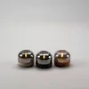 Three LED candles with smoky glass covers and different colored bases are arranged in a row against a plain gray background. Produktbild-Vorschau