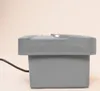 A side view of a gray electronic device with a black power cord. Produktbild-Vorschau