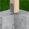 A wooden post is anchored into a concrete base with a metal bracket and screws. Green grass is visible in the background. Náhľad obrázku produktu