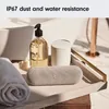 A light gray Beats Pill speaker is placed on a tray in a bathroom setting, next to a soap dispenser and a rolled towel. Náhled obrázku produktu