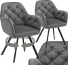 Two grey velvet armchairs are shown, one in the foreground and one in the background. The armchair in the foreground has arrows indicating it can swivel. Náhled obrázku produktu