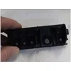 A hand holding a black plastic component with several circular openings, some containing small metallic or mesh inserts. Produktbild-Vorschau