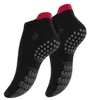 A pair of black ankle socks with red trim and grey grip dots on the sole. Produktbild-Vorschau