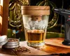 A whiskey glass with a wooden lid, a smoking gun, and a tin of wood chips are arranged on a wooden surface, suggesting a whiskey smoking experience. Voir les images du produit