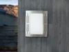 A modern outdoor wall lamp mounted on a concrete wall, with stairs and a mountain landscape in the background. Anteprima dell’immagine prodotto