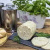 A food preparation setup with a meat smoker, a loaf of cooked meat, sliced meat, bread rolls, and fresh herbs. Produktbild-Vorschau