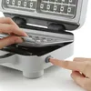 A close-up shot of hands interacting with a waffle maker. Produktbild-Vorschau