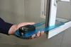 A hand holding a digital measuring tool against a window frame. Produktbild-Vorschau