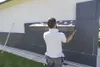 A man is installing insulation panels on the exterior wall of a building. Produktbild-Vorschau