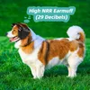 A dog wearing earmuffs stands in a grassy field. Produktbild-Vorschau