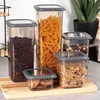 A collection of five clear plastic food storage containers with gray lids, filled with various dry goods, arranged on a wooden cutting board. Anteprima dell’immagine prodotto