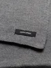 A close-up shot of a gray knitted scarf with a black label. Anteprima dell’immagine prodotto
