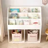 A white children's bookshelf filled with books and storage bins. Podgląd zdjęcia produktu