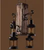 A rustic chandelier made of wood and metal with four lantern-style lights. Náhled obrázku produktu
