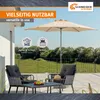 A patio set with chairs, a table, and a large umbrella on a paved patio with a grassy background. Produktbild-Vorschau