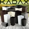 A collection of various square planters of different sizes and colors arranged on a wooden surface with a green leafy background. Podgląd zdjęcia produktu
