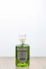 A bottle of green absinthe sits on a wooden surface against a white background. Produktbild-Vorschau