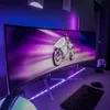A gaming setup with a curved monitor, keyboard, mouse, and headphones, illuminated by purple LED lights. Náhľad obrázku produktu