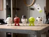 Five decorative figures resembling sports balls are lined up on a wooden table. Produktbild-Vorschau