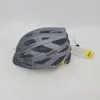 A grey Uvex bicycle helmet with yellow accents is displayed on a white background. A tag with 'Mips' and 'Safety for Helmets' is attached to the helmet. Produktbild-Vorschau