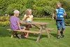 Three children are playing and sitting around a wooden picnic table in a garden. Produktbild-Vorschau